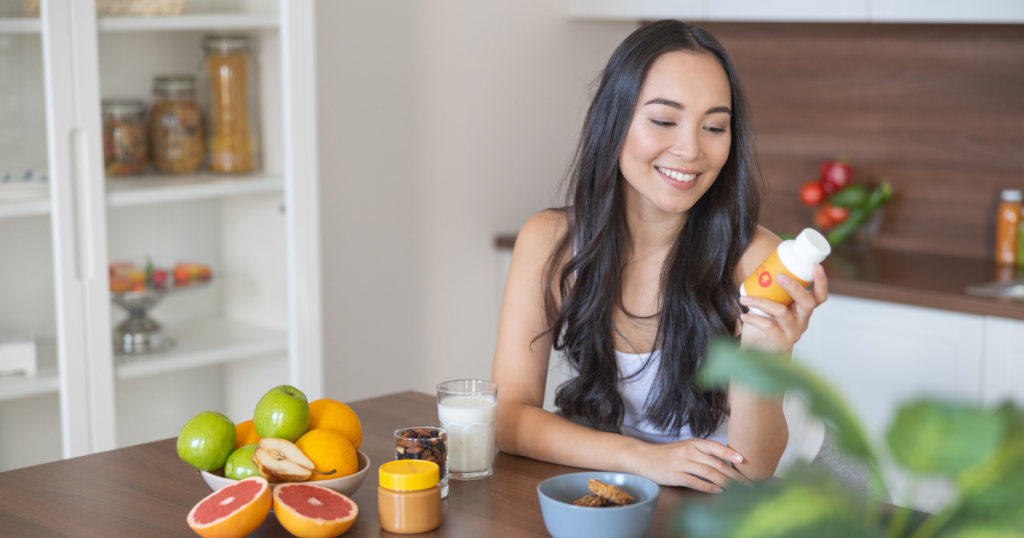 Smiling woman reads the information on the supplements bottle.