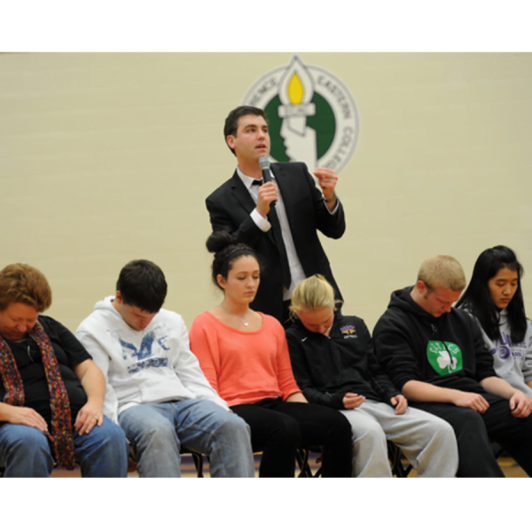 Stage hypnotist performs hypnosis for an audience.