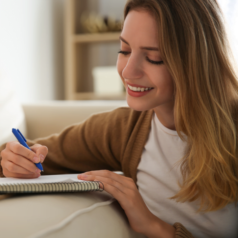 Woman writing out positive affirmations for her self-hypnosis session.