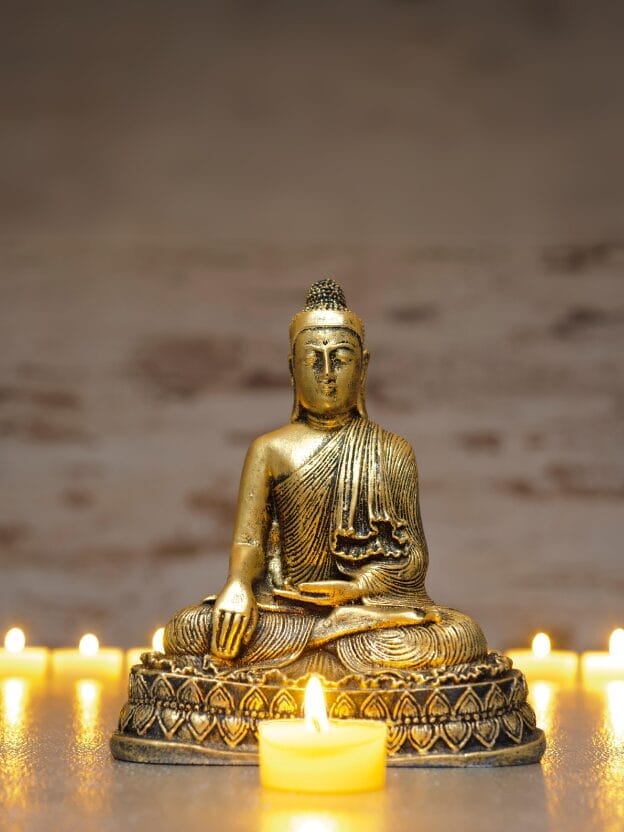 Candles surround a statue of Buddha.